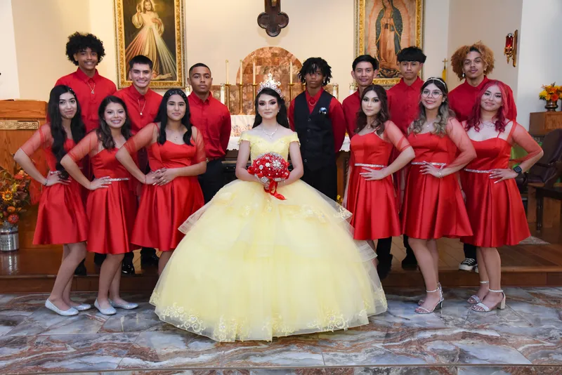 Quinceañera con vestido amarillo y tiara posando con su corte de honor en una iglesia de Phoenix.