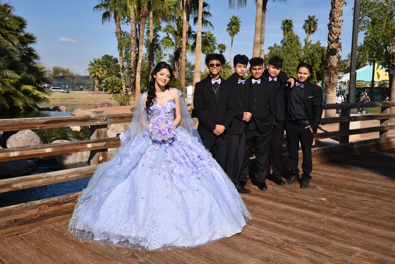 Quinceañera con vestido lavanda y chambelanes posando en puente de madera durante sesión fotográfica en Phoenix.